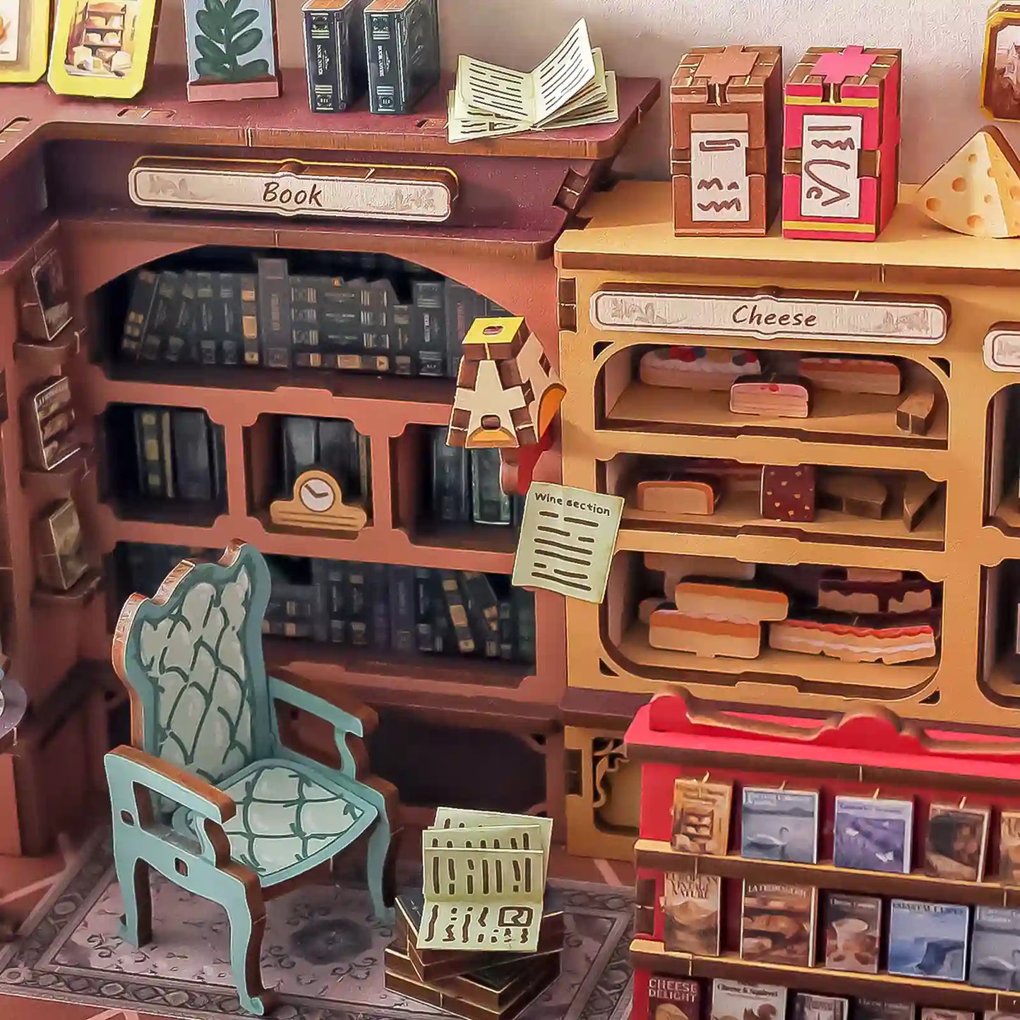 A miniature wooden bookshelf and counter display with toy books, labeled boxes, a small chair, and shelf accessories arranged in a detailed room-like setup.