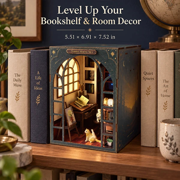 A decorative bookshelf box displayed on a wooden shelf, surrounded by faux books. The box features a miniature bookroom scene with a glowing window, shelves, and a small cat figurine.