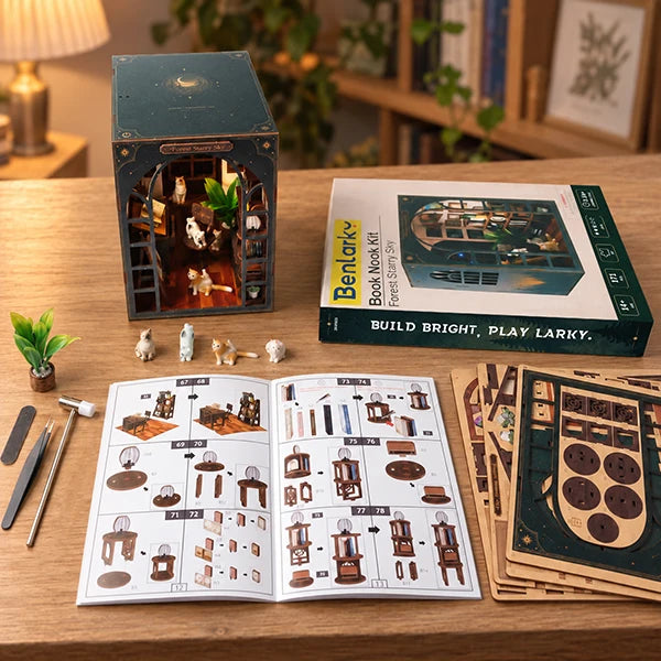 A wooden book box DIY kit displayed on a wooden table with its packaging box, instruction booklet, and wooden pieces. The assembled miniature book box is shown on the left, the instruction sheet is open in the center, and the remaining wooden components are stacked on the right.